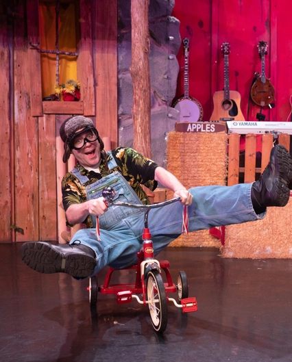 performer at The Comedy Barn riding tricycle